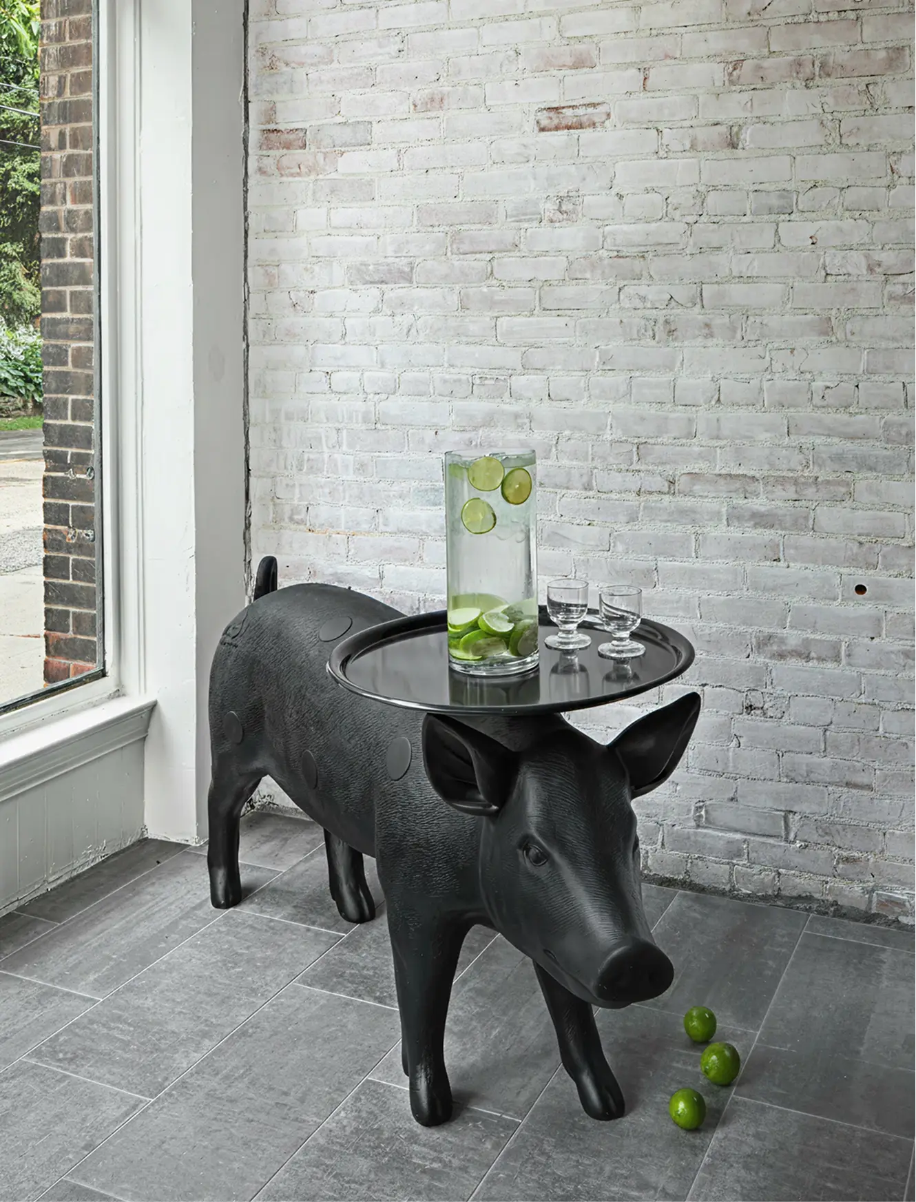 A cast sculptural side table set against a brick wall at Sens Commons